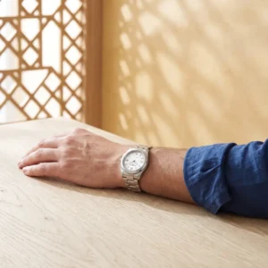 Poignet masculin portant une montre acier a cadran blanc